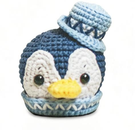 Handmade chubby blue and white penguin crochet stuffed animal. A kawaii, round amigurumi plushie wearing a cute light blue hat and matching collar, perfect as a winter desk pet or a finished handmade gift.