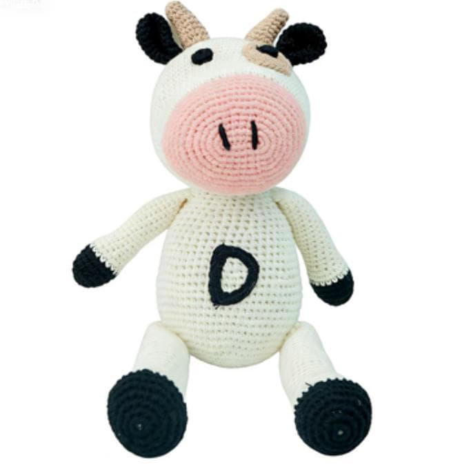 Front view of a handmade crochet cow plush toy with a soft pink snout and black hooves on a white background.