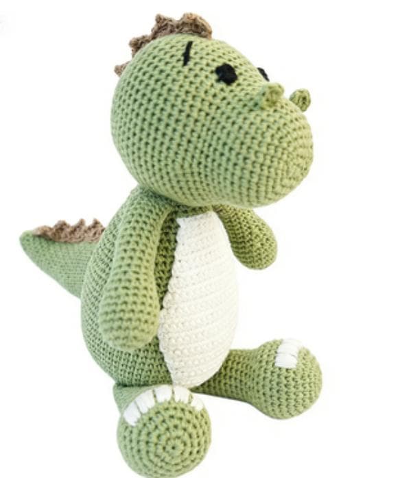 A soft, crocheted green dinosaur plush sitting upright. It features a large white belly, cute white embroidered claws on its feet, and row of small brown spikes running down its back to its tail.