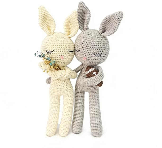 Handmade sleeping bunny couple crochet stuffed animals. A pair of ragdoll-style amigurumi rabbits in cream and grey, featuring closed eyes and holding tiny flowers and a football, perfect as romantic couple gifting, nursery decor, or finished plush toys.
